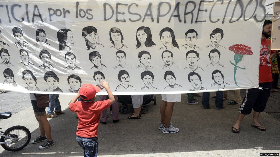 Child looking at a banner showing people who have been disappeared