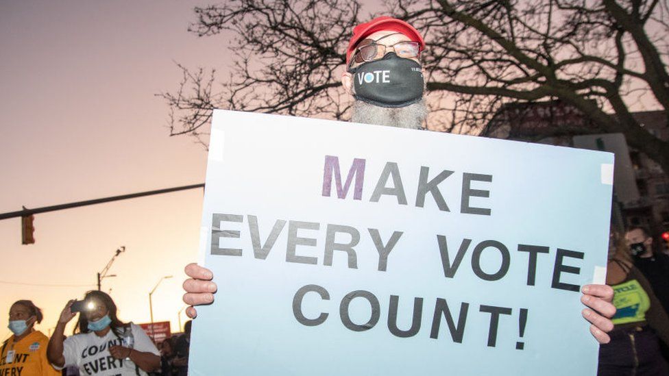 A protester in Michigan holds up a sign that says "Make Every Vote Count"