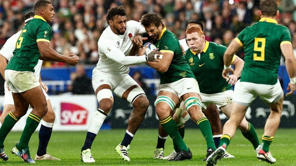 Courtney Lawes in white strip attempts to take the ball off a green-shirted player