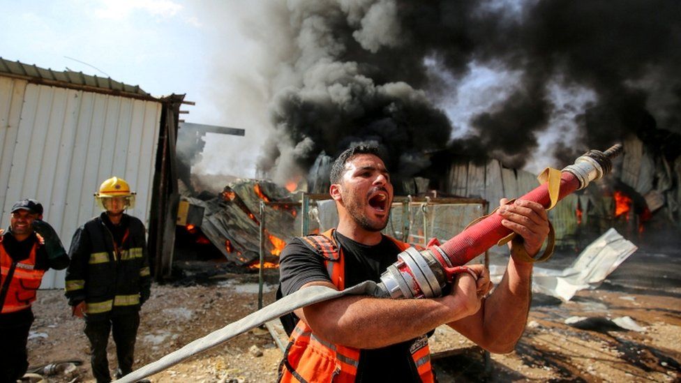 A Palestinian firefighter reacts as he participates in efforts to put out a fire at a sponge factory