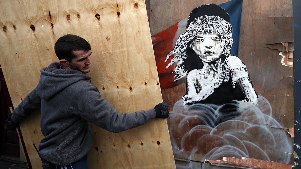 Builders cover a Banksy artwork on a building opposite the French embassy