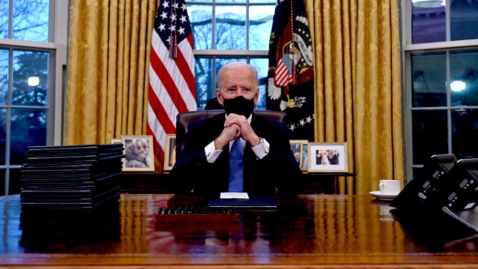 President Biden sits at his desk in the Oval Office