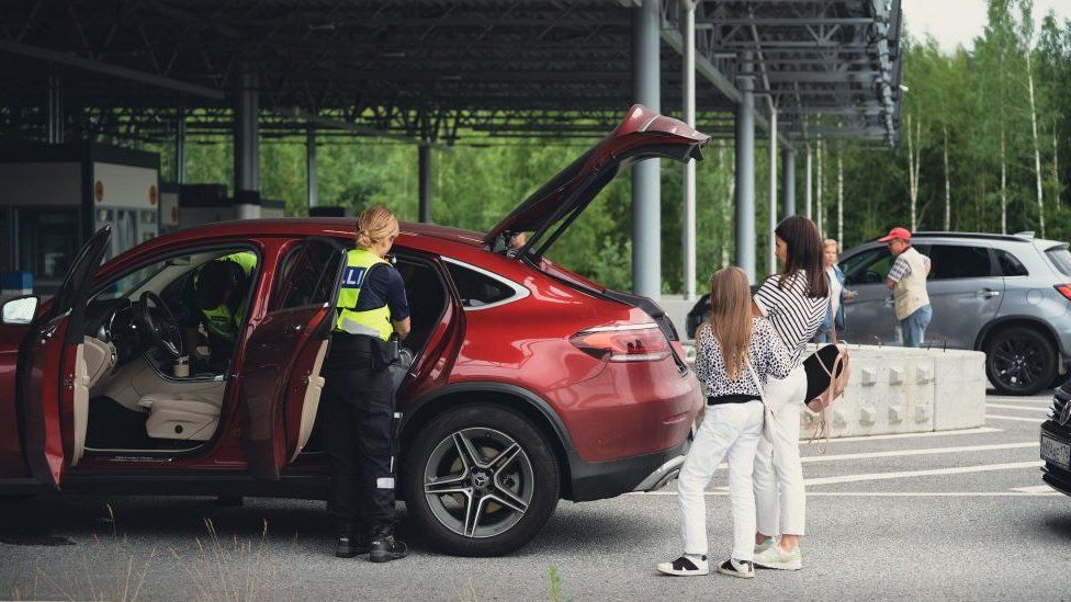 A customs officer checks a Russian car at the border with Finland in July