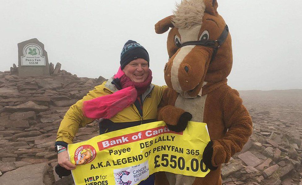 Des at the summit receiving a cheque for £550 from a person dressed up as a horse