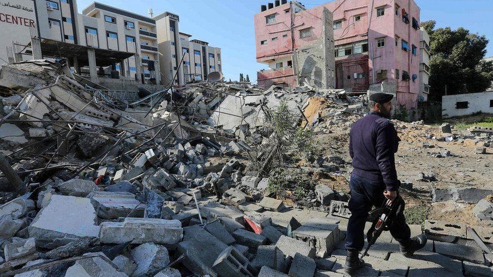 Hamas policeman walks past the remains of a building in Gaza City destroyed in an Israeli air strike (26 March 2019)