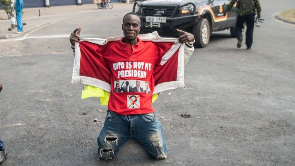 A protester kneels on road while wearing a shirt with the slogan ''Ruto is not my president'' during a countrywide protest