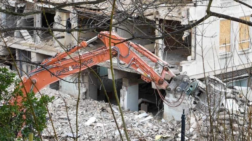 Crane demolishing building