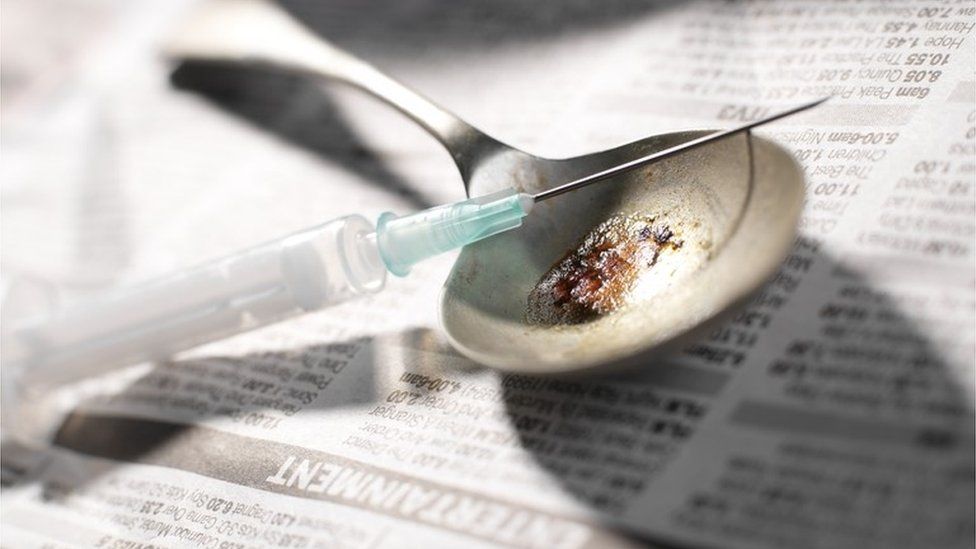 Hypodermic needle and syringe with a pile of heroin on a spoon