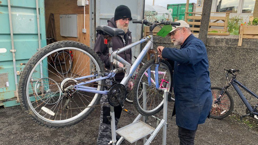 Members of Portstewart Men's Shed fixing the brakes on a bike