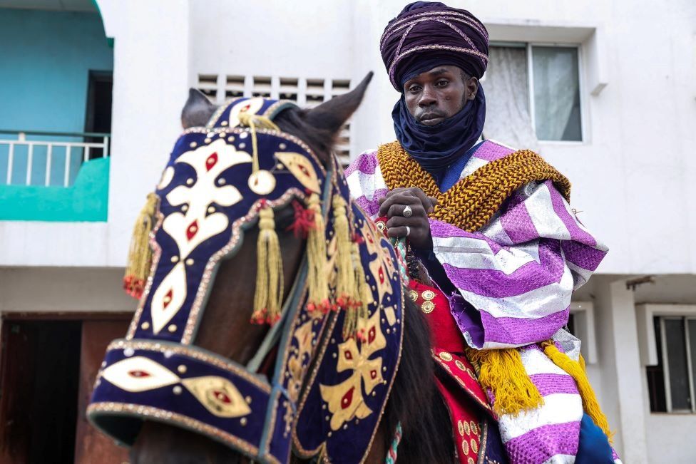 A man on a horse. Both are adorned in bright colours.