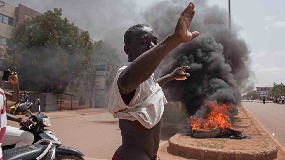 A Burkina Faso protestor gestures in front of burning tires as he and others take to the streets in the city of Ouagadougou, Burkina Faso, Thursday, 17 September 2015