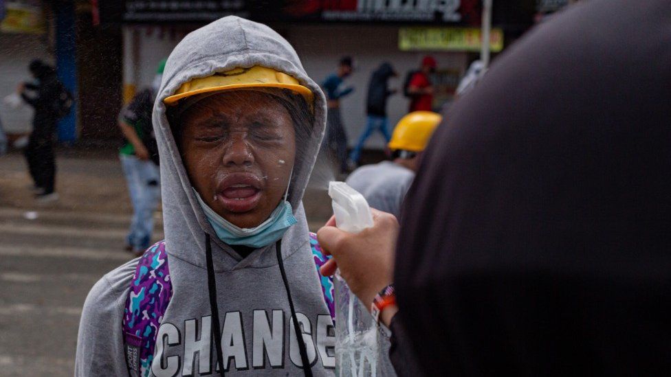 Лицо женщины опрыскано уксусом, чтобы противодействовать воздействию слезоточивого газа на акции протеста в Медельине 2 июня 2021 года