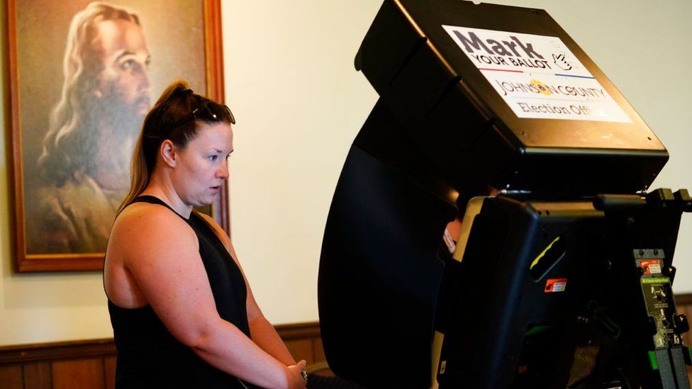 A poll worker inside a church near a picture of Jesus