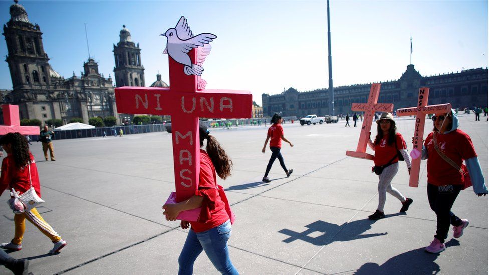 Women carry pink crosses during the protest