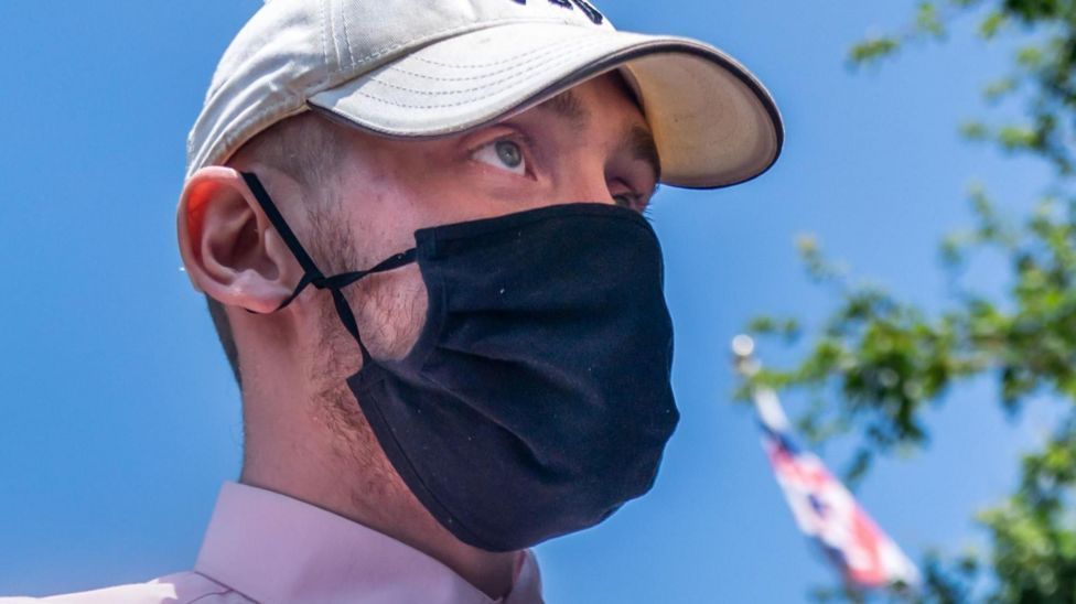 A man wearing a black face mask and a hat