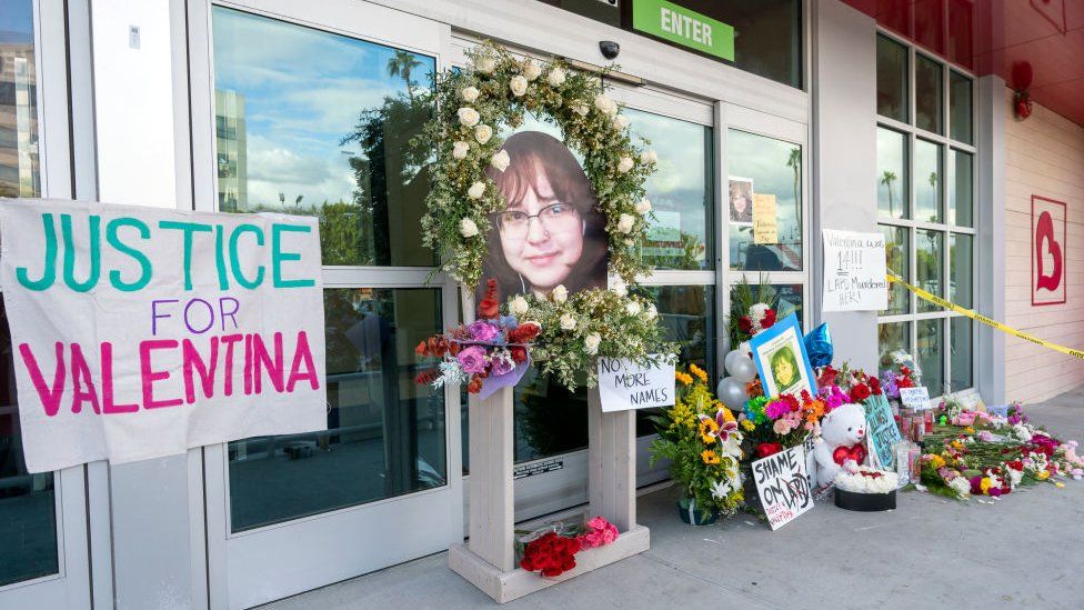 Placas dizendo "Justiça para Valentina" e flores do lado de fora da loja de departamentos