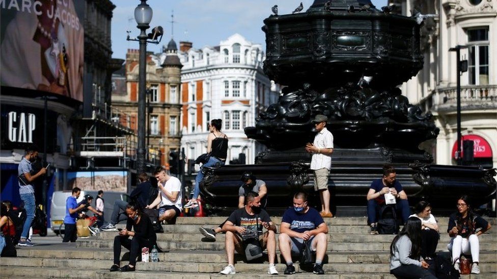 People sit on steps at Piccadilly Circus, amid the coronavirus disease