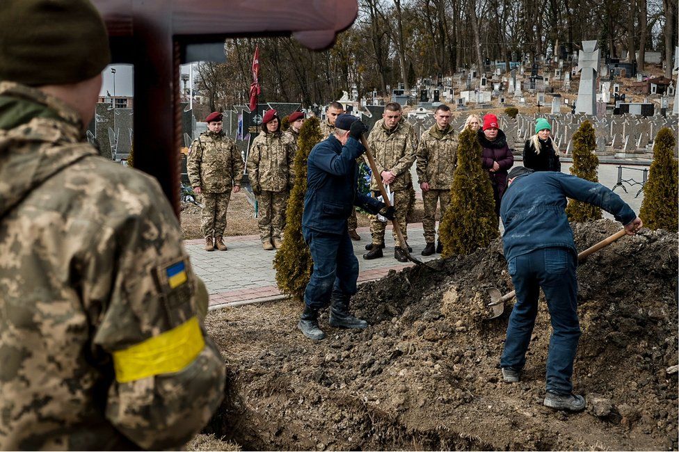 The gravediggers at the Lychakiv Cemetery cover Kotenko's coffin with earth