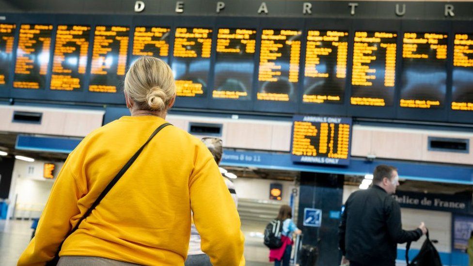 A woman looks at the departures board at Euston Station