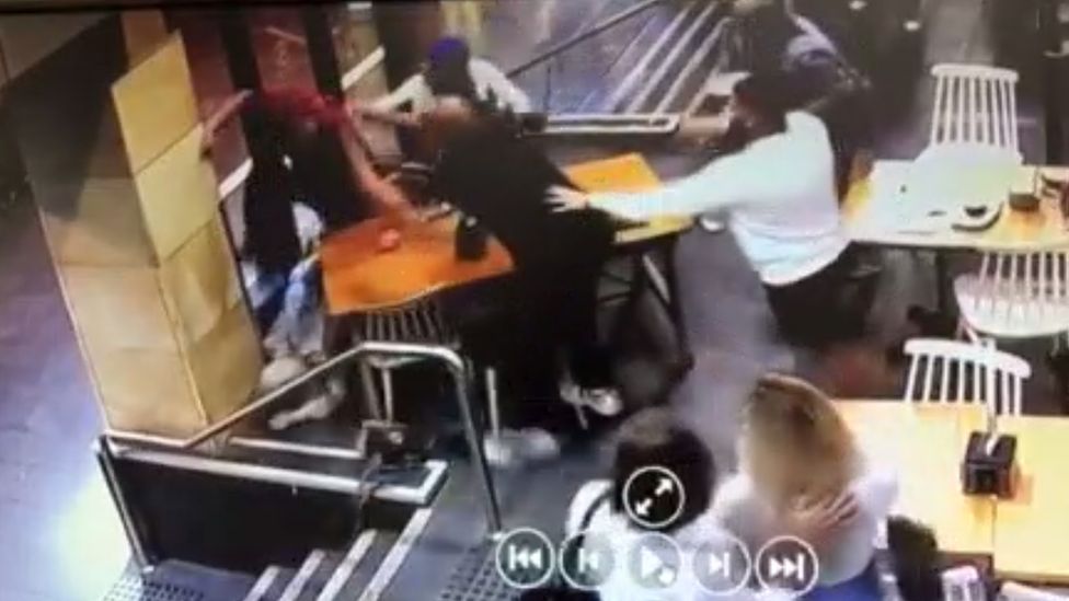 A still from a police video shows other cafe customers pulling Lozina away during his attack on Ms Elasmar