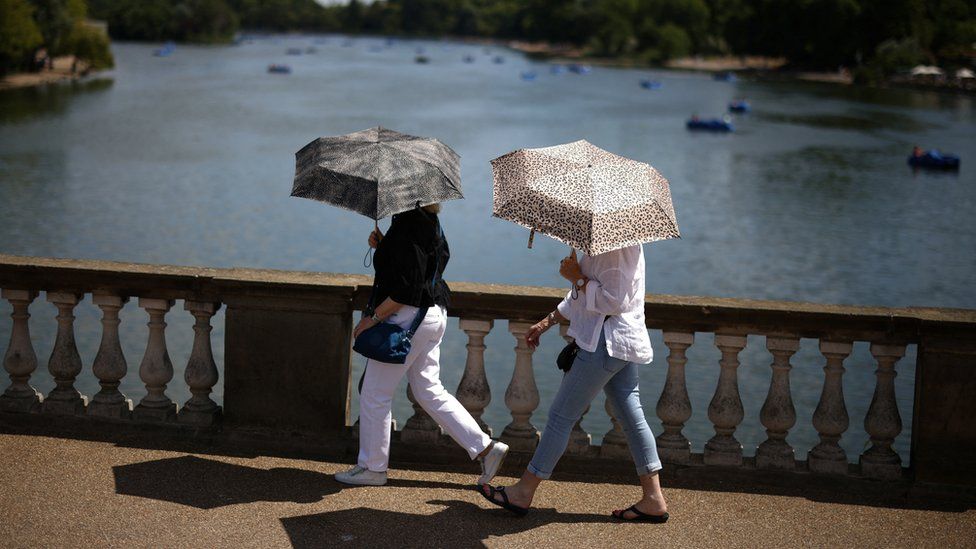 People use umbrellas to shelter form the sun in Hyde park