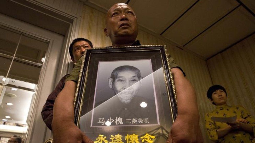 Ma Wenyi,holds a photo of his father who was forced to work during World War II at a mine for Mitsubishi Mining Corp