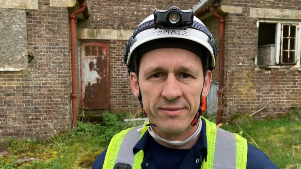 Tomasz is wearing a high-vis jacket and a hard hat