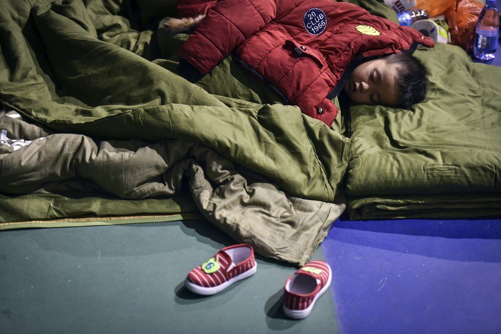 In this photo released by China's Xinhua News Agency, an evacuated boy rests at a makeshift shelter place located at a sports centre in Shenzhen, south China's Guangdong Province Monday, 21 December 2015