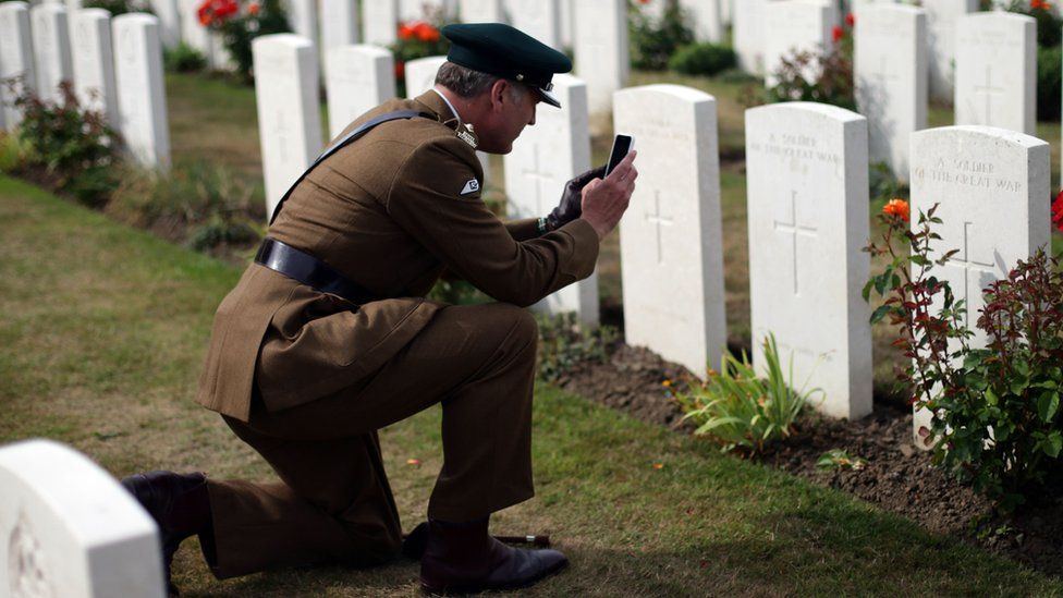 A serviceman takes a photograph in the cemetery