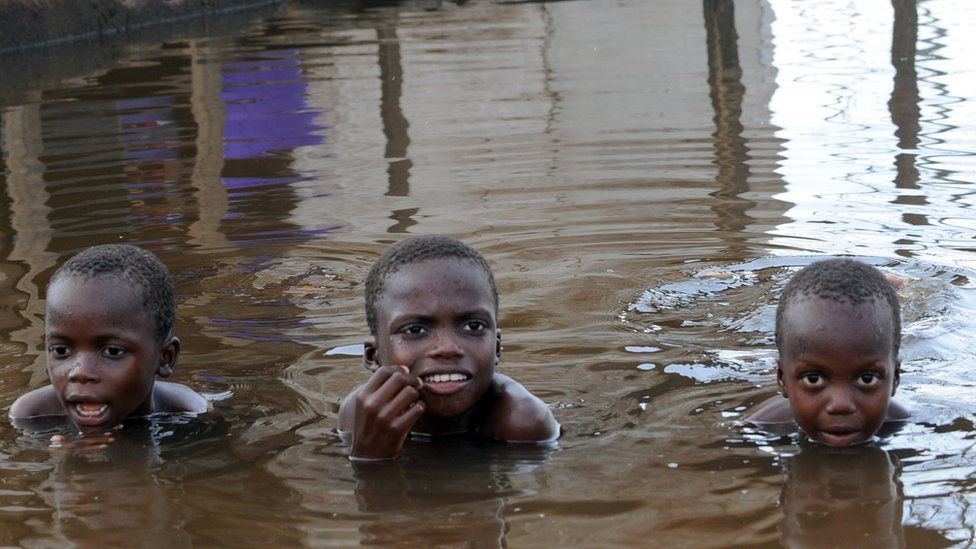 Children pose as they swim in front of a flooded house in the town of Yenagoa, in the Bayelsa oil-rich Niger Delta region, on November 15, 2012.