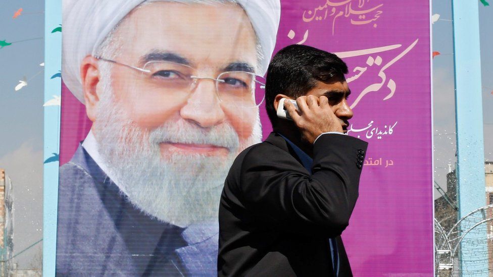 A man walks past an election banner showing President Hassan Rouhani in Tehran, Iran