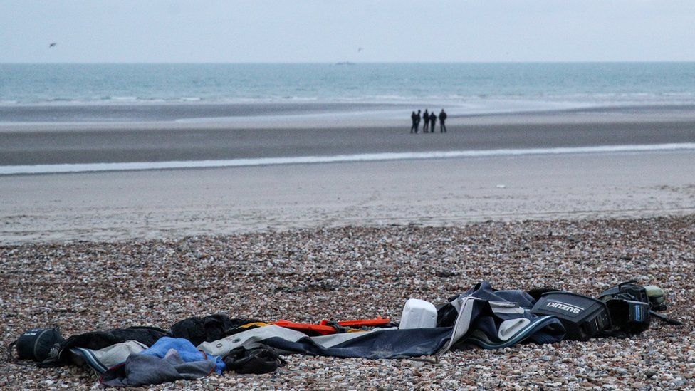 Remains of damaged migrants' inflatable boat and personal belongings left by migrants on the beach near Wimereux, France, 25 November 2021
