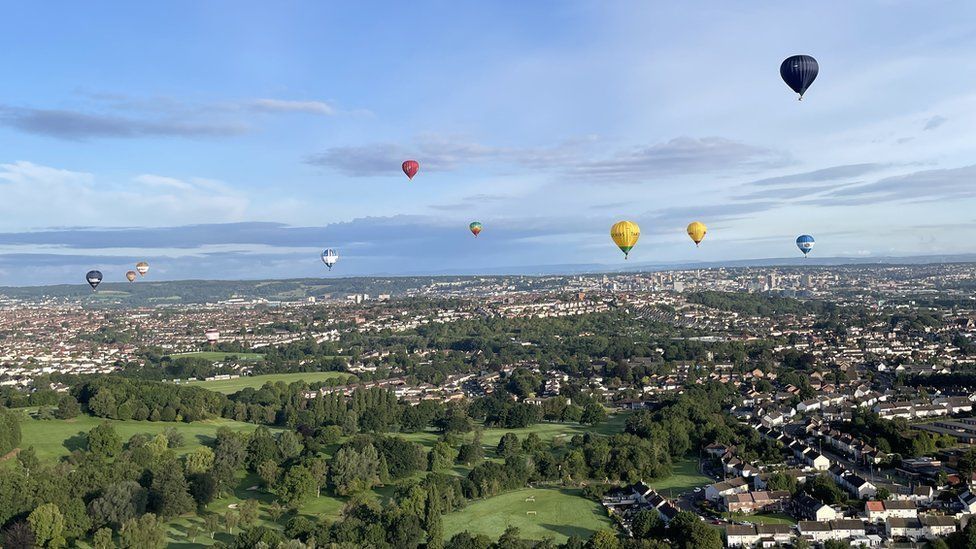 Ten hot-air balloons high up in the sky over the view from Dundry Hill