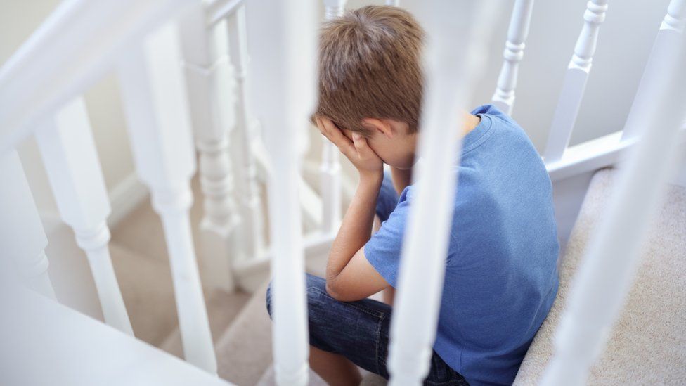 Boy sitting on stairs with head in hands