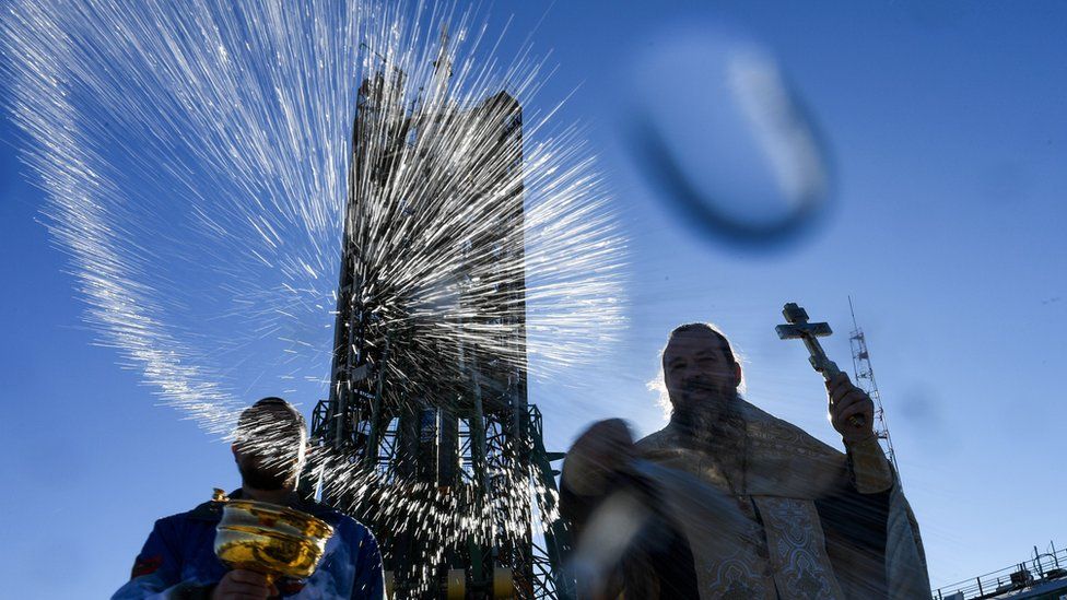 Image of a Russian Orthodox priest blessing the Russian Soyuz rocket capsule.