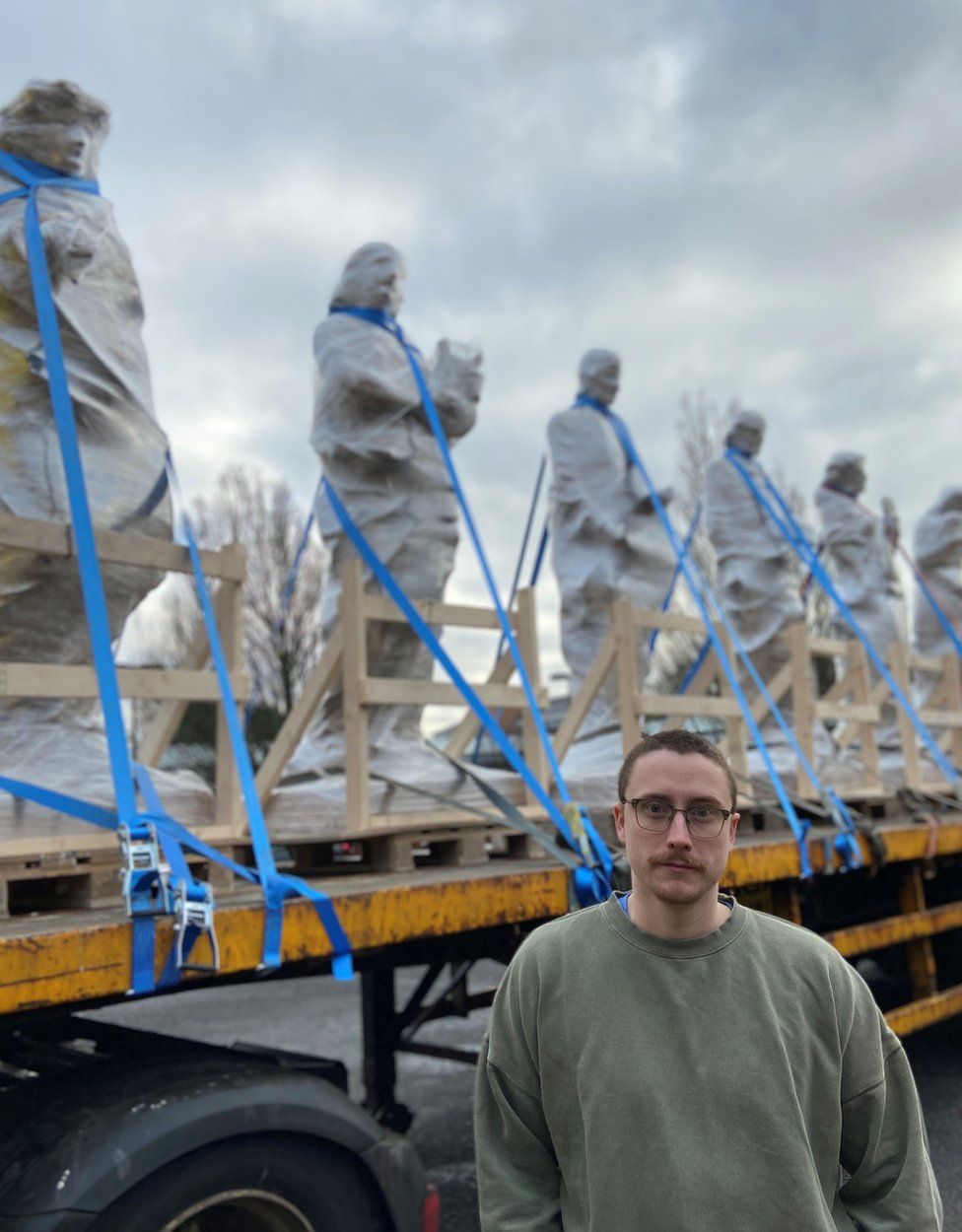 Sculptor David J Mitchell with statues on truck in background