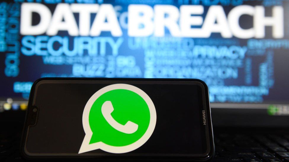 In this photo illustration, the Whatsapp logos is seen on a Huawei smartphone with the word Data breach on a laptop monitor