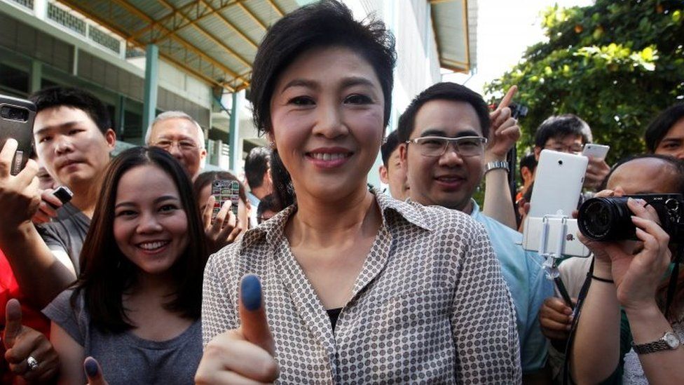 Former Thai Prime Minister Yingluck Shinawatra (centre) shows her inked finger after casting her vote in Bangkok