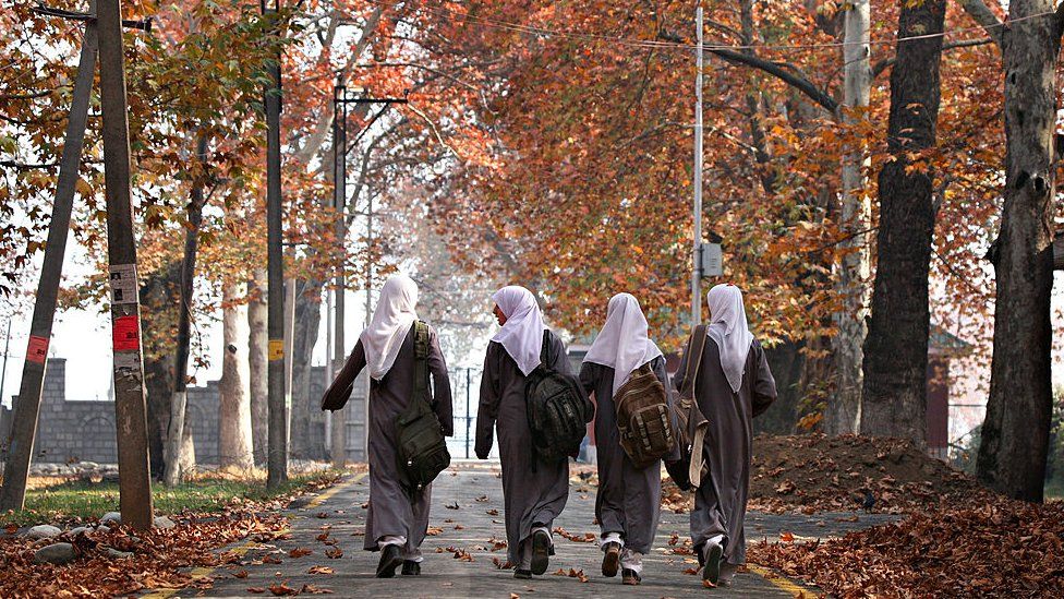 Kashmiri Muslim women walk down a lane past autumn foliage at a university campus in Srinagar on November 12, 2008.