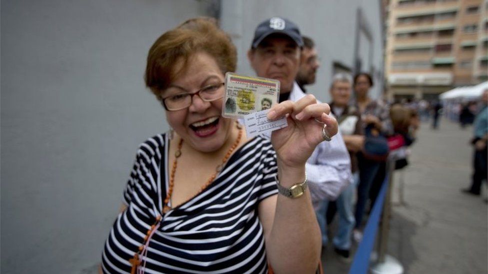 A woman shows her identification card before entering to validate her signature at the Venezuelan National Electoral Council, CNE, headquarters in Caracas, Venezuela, Monday, June 20, 2016.