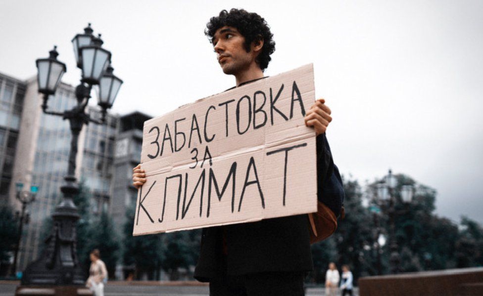 Protester Arshak holds a sign reading "climate strike" in Moscow