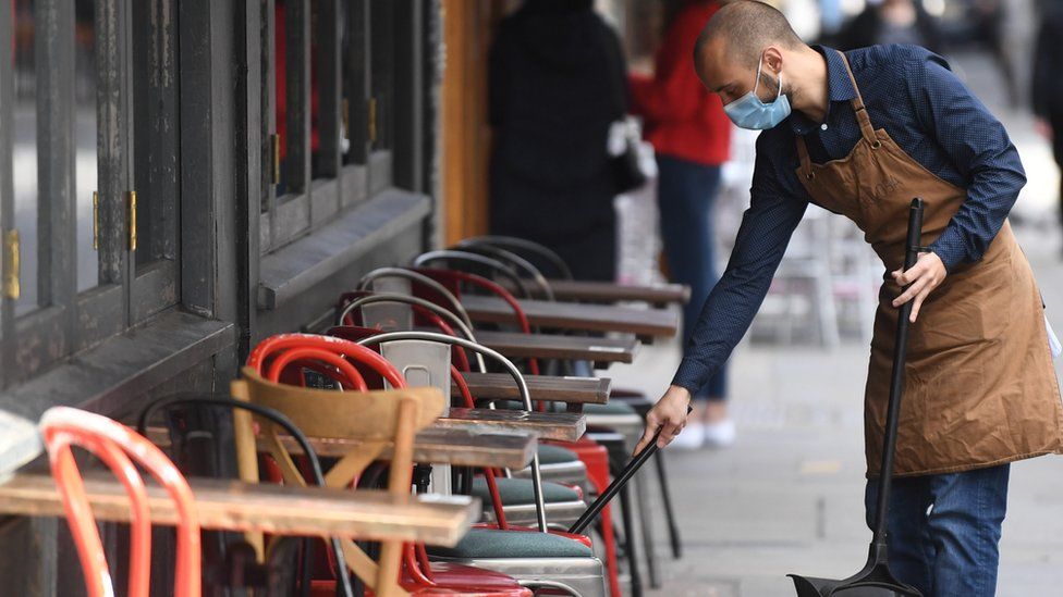 Man cleans outside seating of London pub