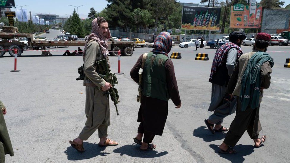 Taliban fighters patrol along a blocked street ahead of the council meeting of tribal and religious leaders in Kabul