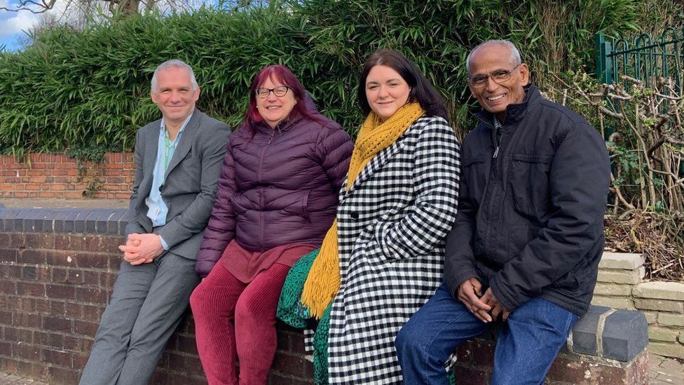 Four council members and people from Friends of Kingswood park sat in a row on a brick wall