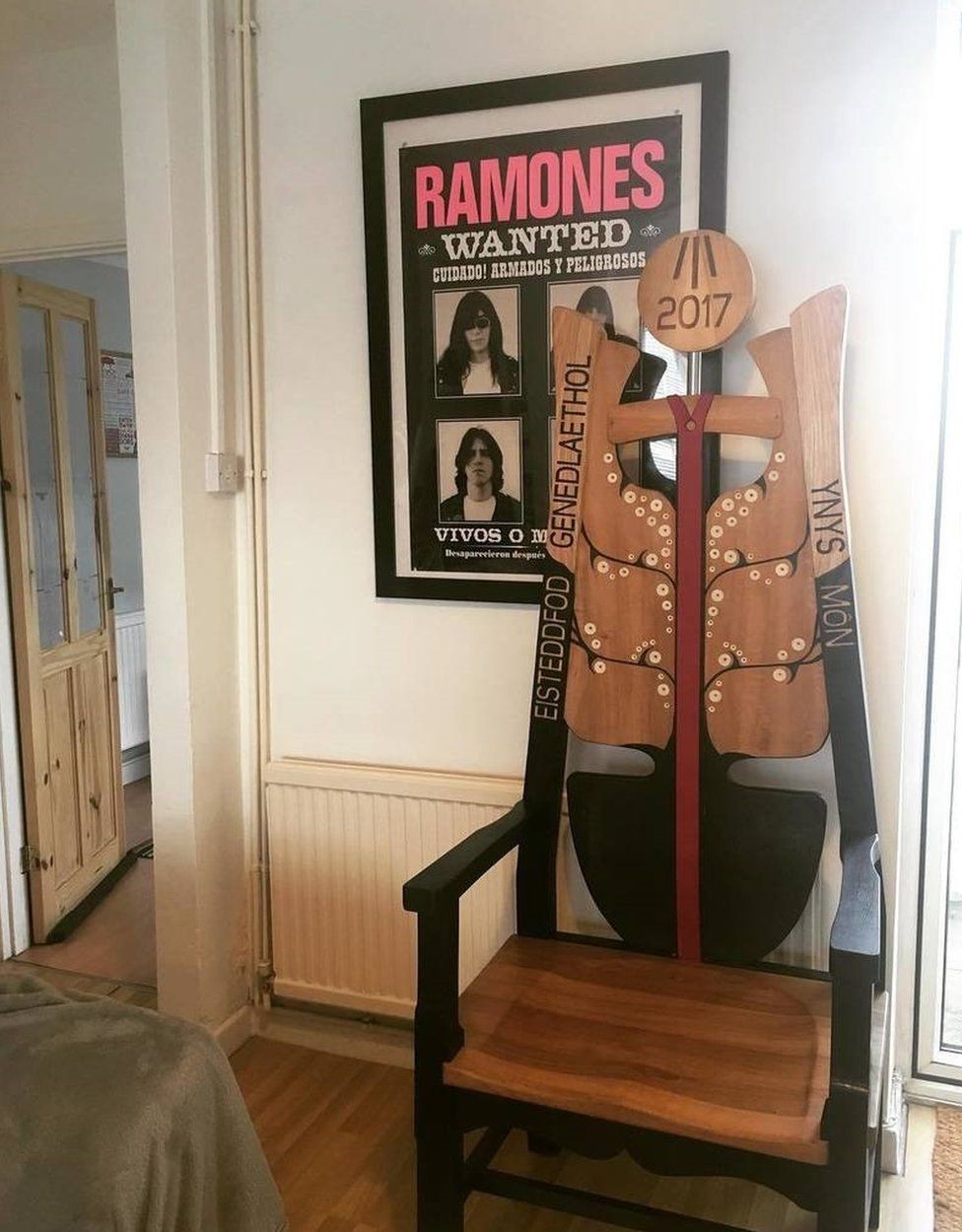 Cadair Eisteddfod Sir Fôn eleini yn ei chartref newydd, o dan poster y Ramones
