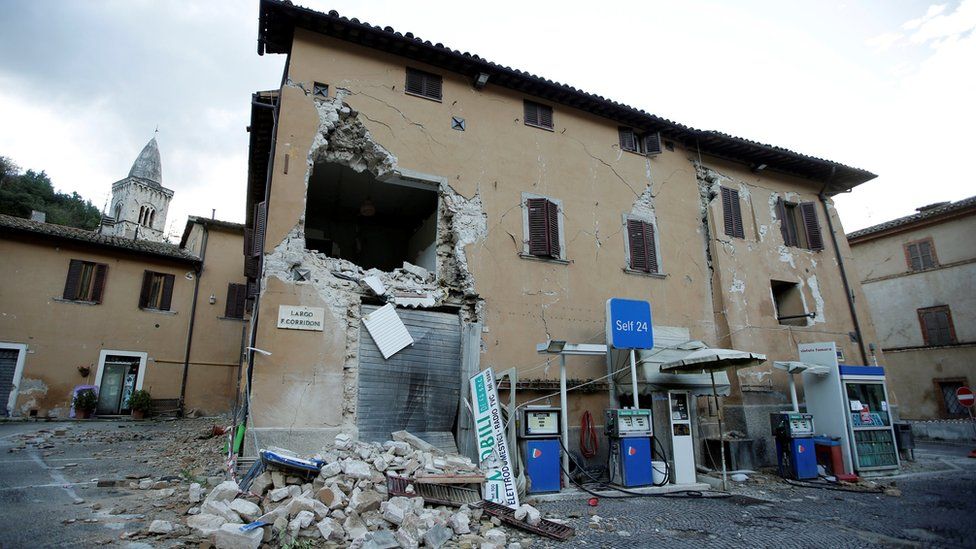 A collapsed building is seen next to a petrol station after an earthquake in Visso, in central Italy