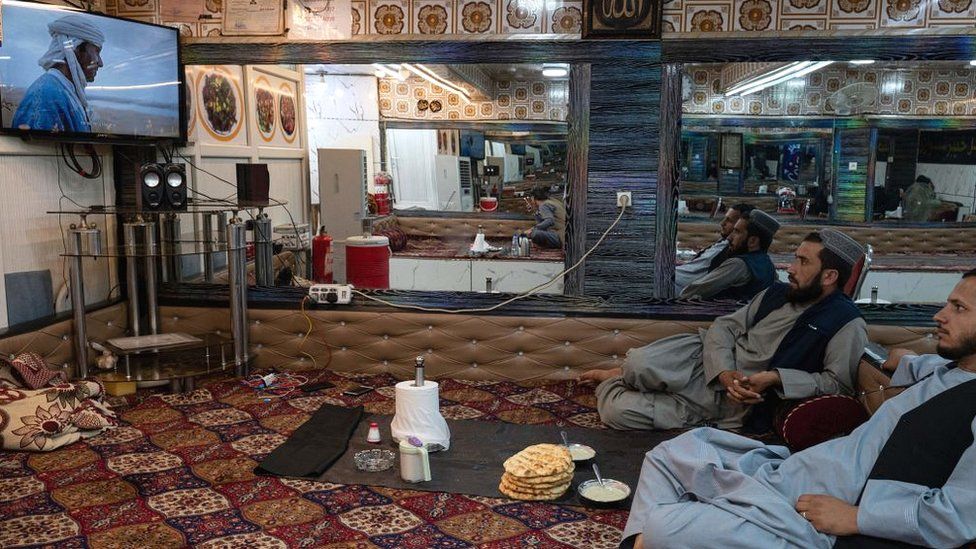 Afghan men watch television in a restaurant in Kabul in August 2022