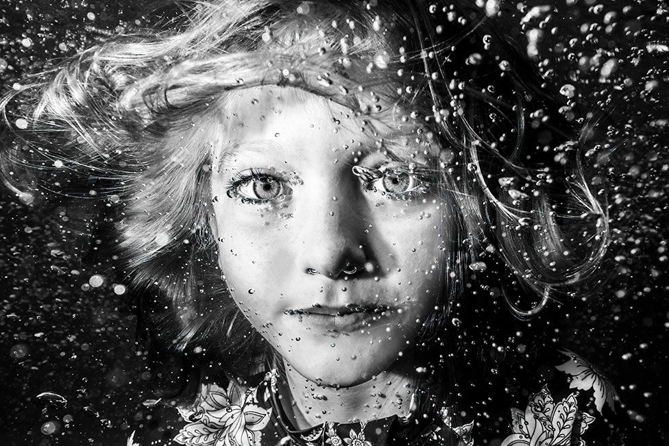 A black and white portrait of a girl underwater