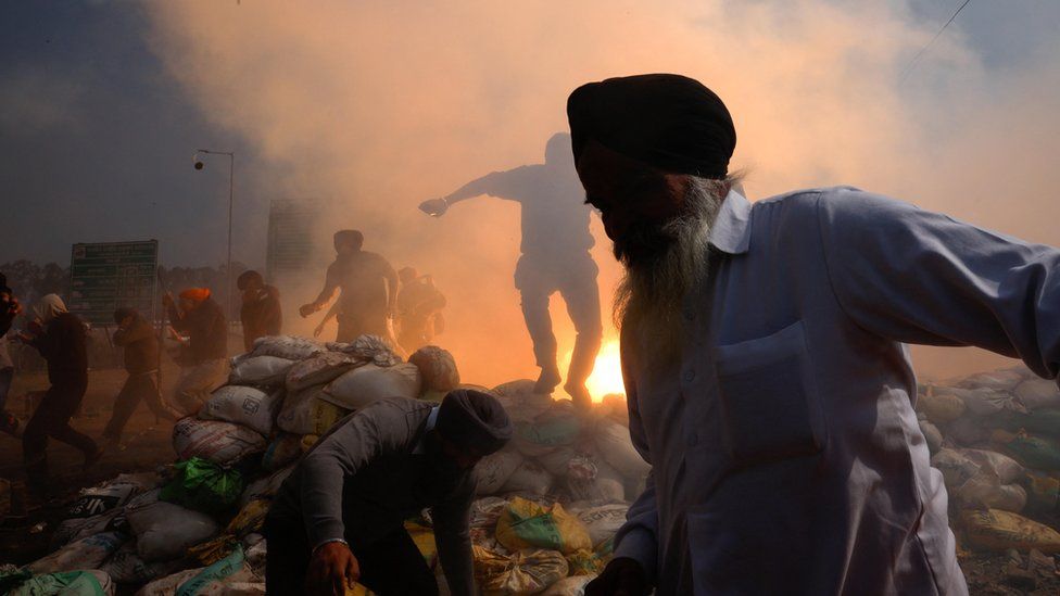 Farmers, who are marching towards New Delhi to press for better crop prices promised to them in 2021, run for cover amidst tear gas fired by police to disperse them at Shambhu barrier, a border crossing between Punjab and Haryana states, India, February 21, 2024