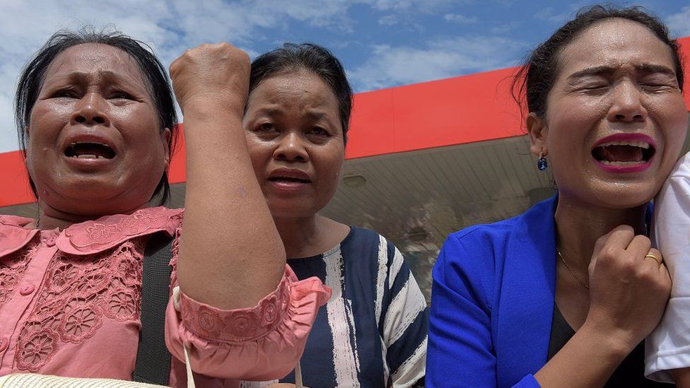 Cambodian women cry outside a convenience store where independent political and social analyst Kem Ley was shot dead in Phnom Penh on 10 July 2016